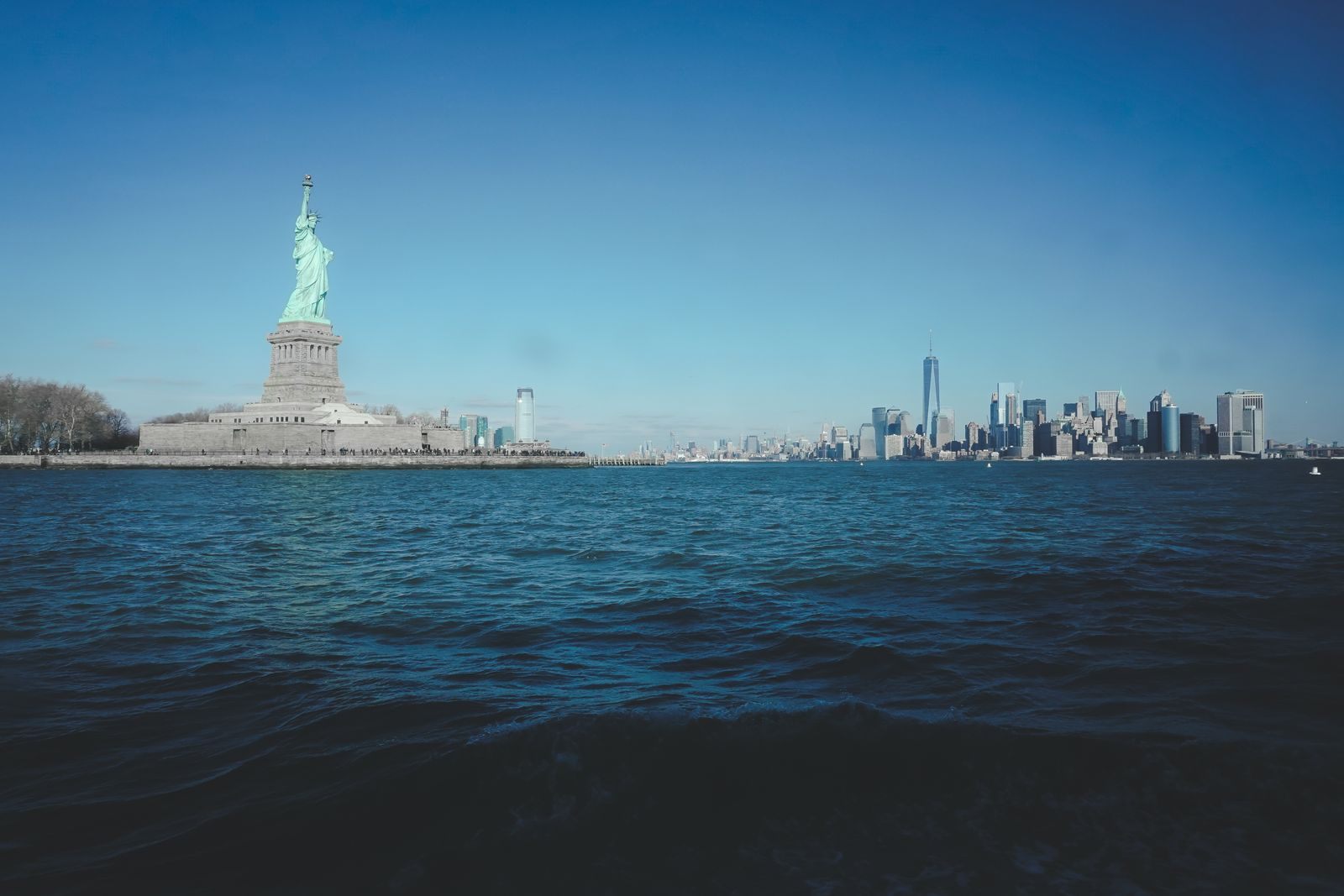 Statue of Liberty and the Manhattan skyline across New York Harbor, where last minute cruises from New York sail