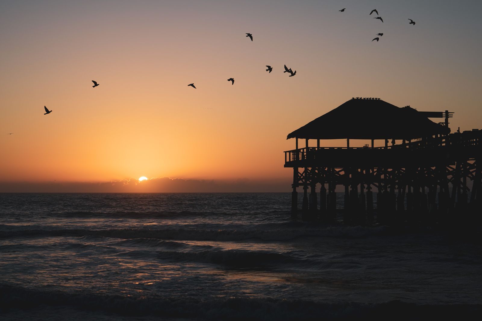 Cocoa Beach Pier silhouetted at sunrise near the terminals for last minute cruise deals from Port Canaveral