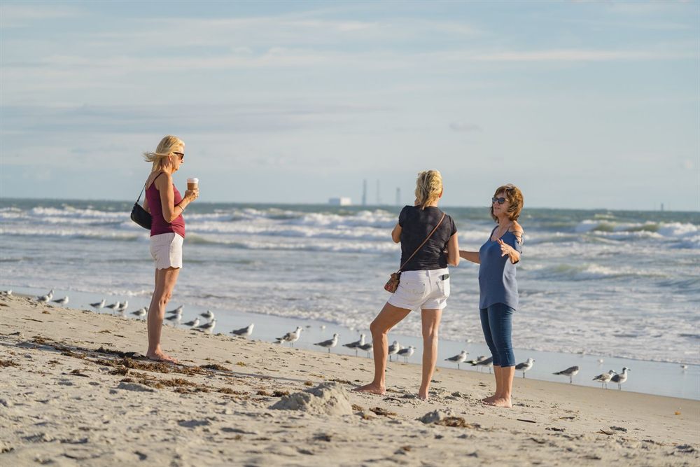 Friends walking on Cocoa Beach, Florida, with seagulls at the water edge
